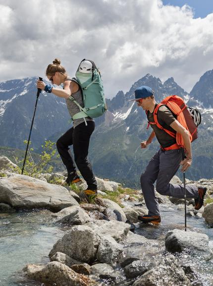 A woman and a man with deuter backpacks hiking up a moutain