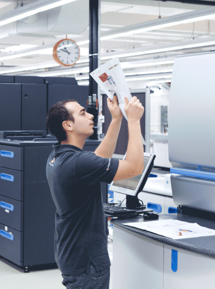 Man checks print product in front of printing machine