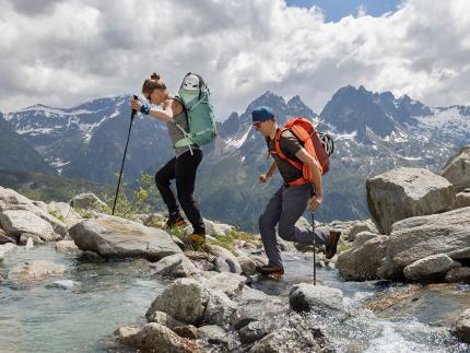 A woman and a man with deuter backpacks hiking up a moutain