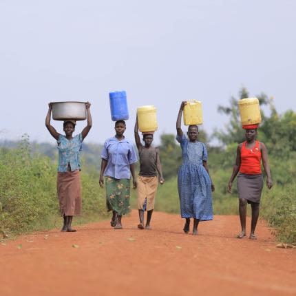 women carrying cans over their heads
