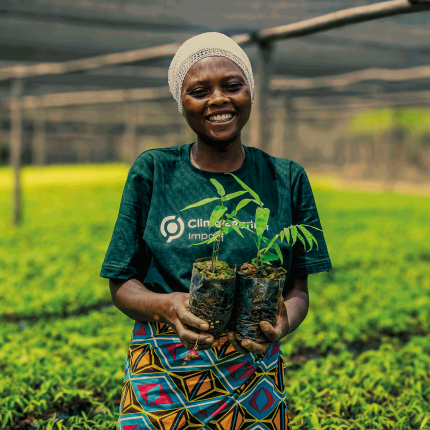 A woman holding two seedlings.