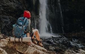 hiking woman sitting at waterfall